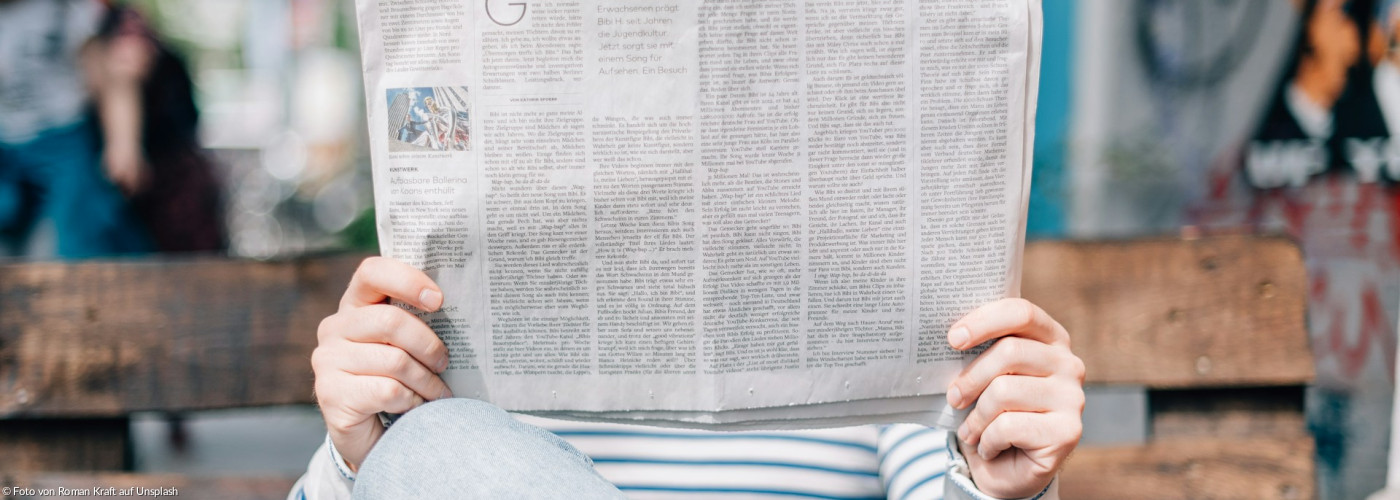 Ein Mann sitzt auf einer Bank und liest Zeitung